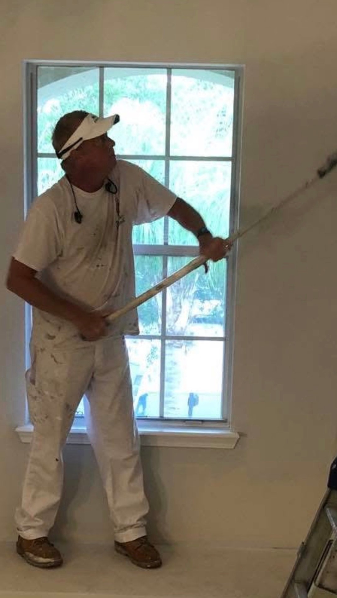A Refresh & Renew painter rolling a wall by an arched window