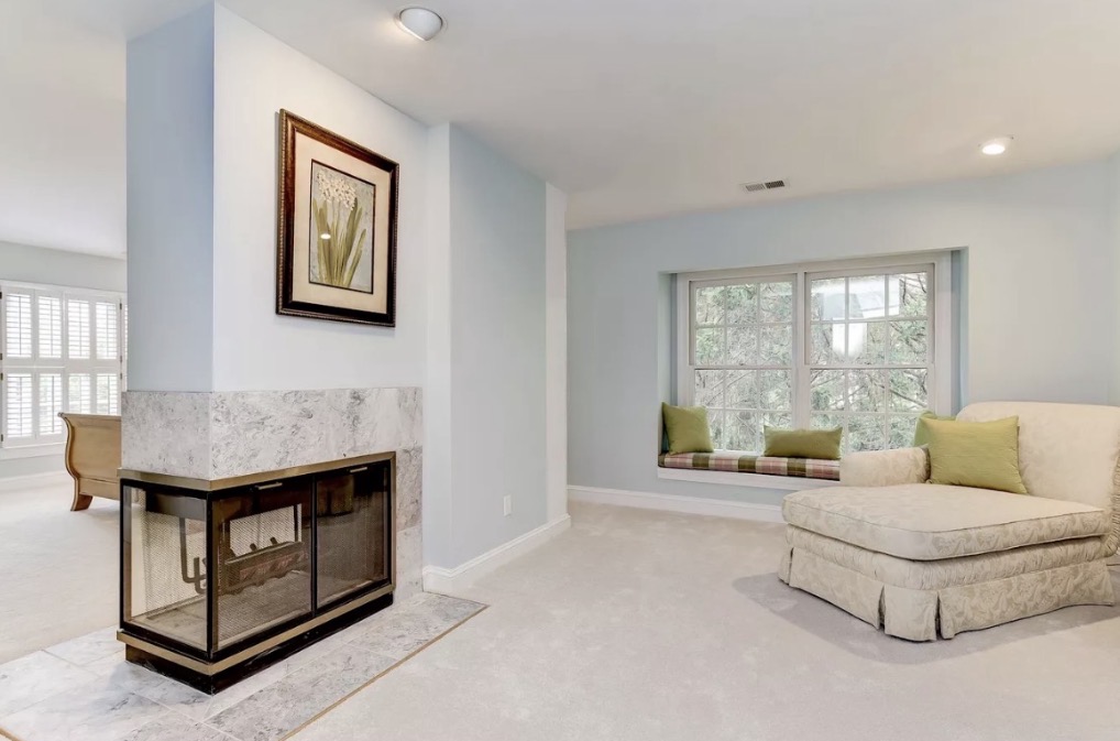 A softly lit sitting room with painted fireplace and window seat, finished by Refresh & Renew